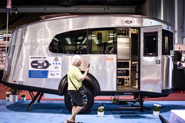Woman standing near chrome RV with open door
