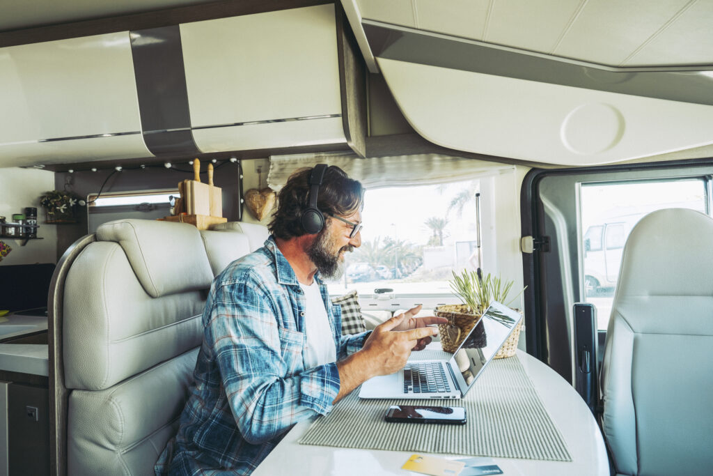 Working and traveling inside motor home camper van concept lifestyle people One man using laptop to video call remote friends sitting on a table in camping car vehicle Digital nomad office new